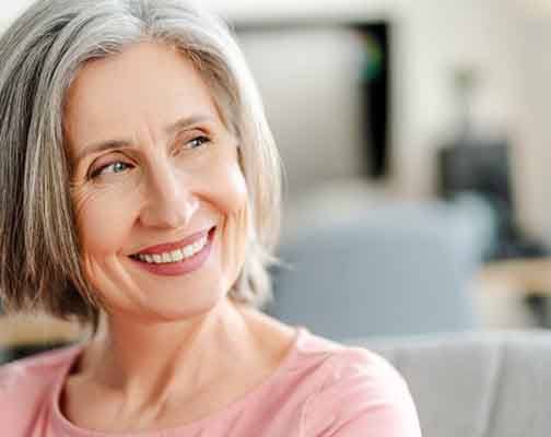 a woman smiling after receiving dental implants